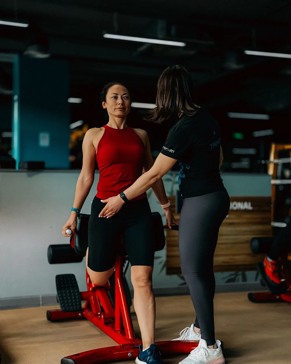 Trainer guiding a client through an exercise, photographed from the side