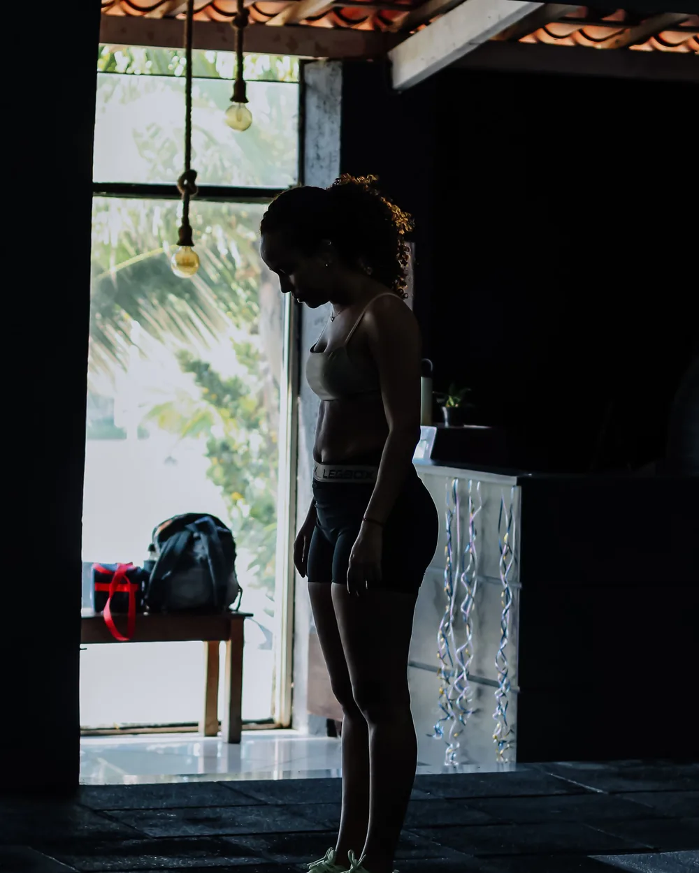 Person standing in a training space doorway, lit from behind by natural light
