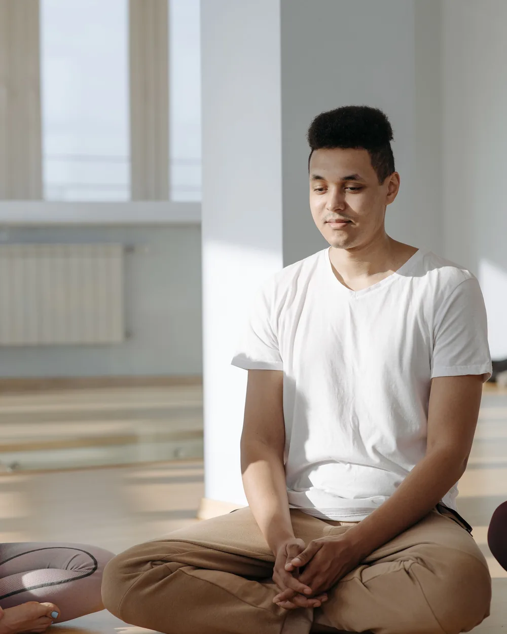 Man sitting cross-legged on the floor of a sunlit room