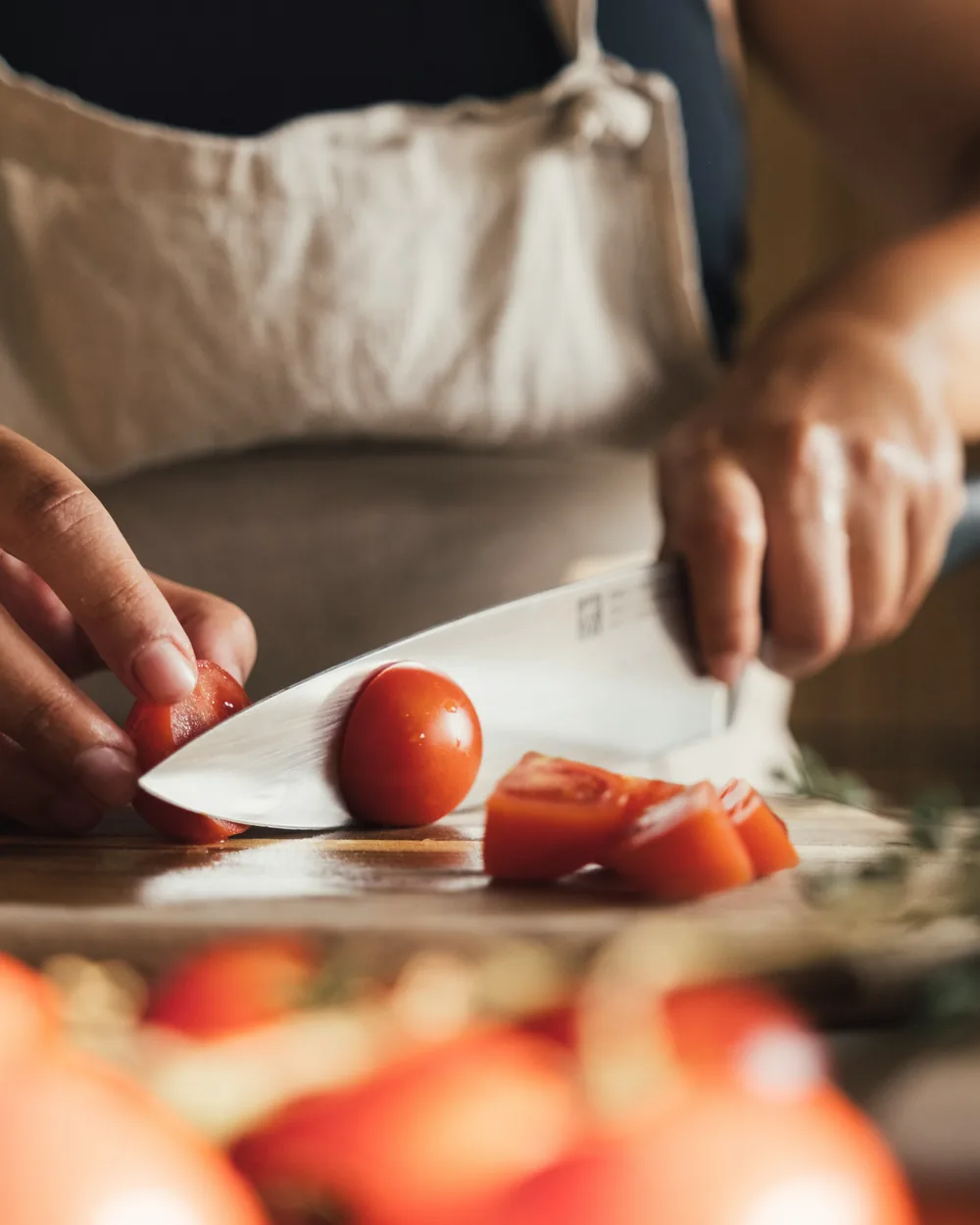 Hands chopping fresh tomatoes on a wooden board