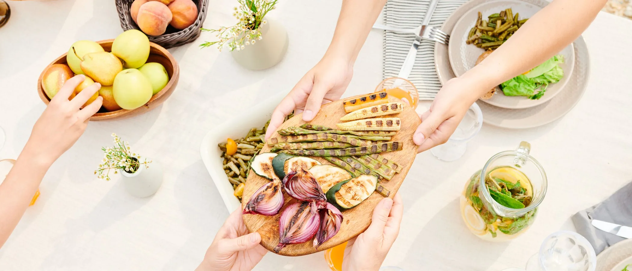 Overhead view of hands passing dishes across a shared table